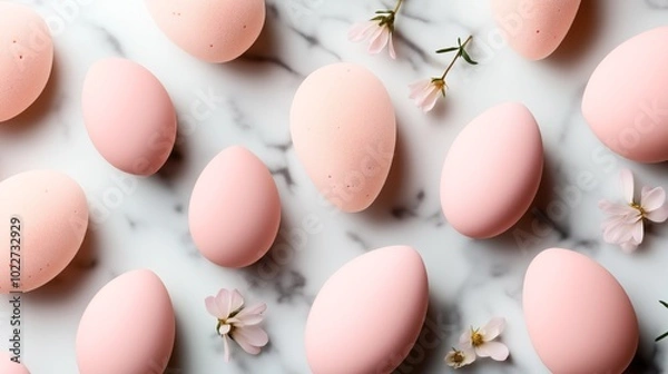 Fototapeta Pastel pink eggs and delicate pink flowers arranged on a white marble surface, creating a soft and serene aesthetic.