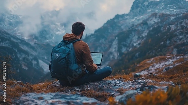 Fototapeta A person working on a laptop in a serene mountain landscape, surrounded by nature and fog, showcasing tranquility and adventure.