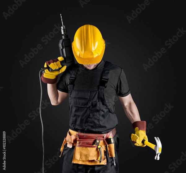 Obraz construction worker in helmet with hammer and drill