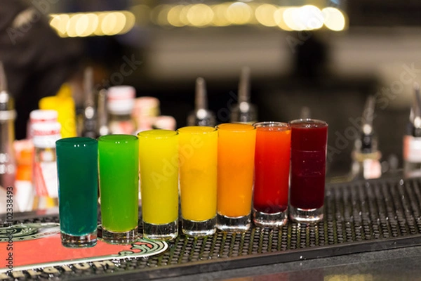 Obraz A group of shot glasses with a rainbow of colored drinks.