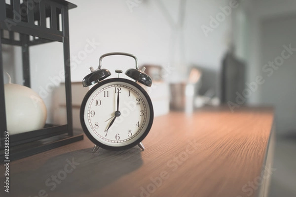 Obraz Toned Photo alarm clock showing 7 o'clock on table in bedroom (Vintage,noise and Grain)
