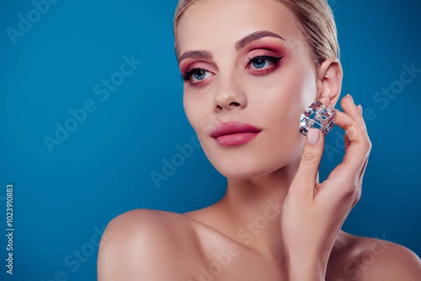 Fototapeta Photo of pretty stunning girl touch ice cube cheek look empty space without clothes isolated on blue color background