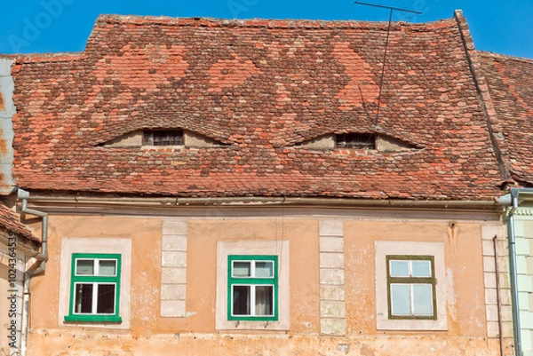Fototapeta A close-up view of a traditional building facade in Sibiu, Romania, featuring a red tiled roof with a distinctive arched shape. 