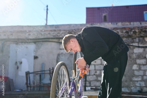 Obraz Young guy fixing a bicycle outside