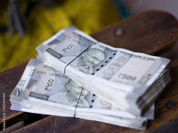 Fototapeta a hand holds multiple bundles of ₹500 Indian rupee notes, neatly stacked and tied with rubber bands, showcasing financial abundance and control over wealth. 