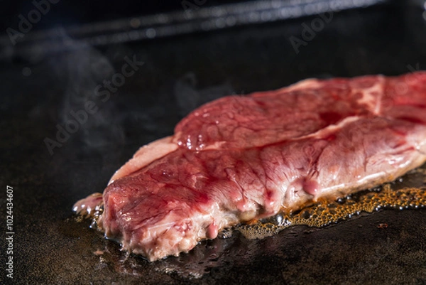 Fototapeta 生の牛肉を鉄板で焼く様子