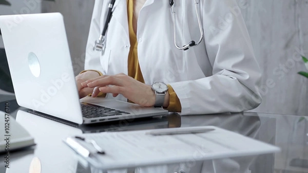 Fototapeta Doctor woman is using a laptop computer on a glass desk in medical office. Work place concept in Medicine