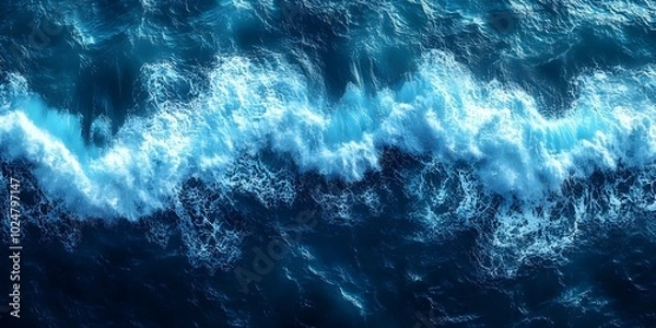 Fototapeta An aerial view of the ocean with waves crashing and creating a beautiful display of whitecaps.