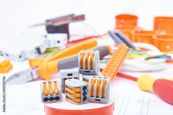 Fototapeta Modern connectors standing on junction box. Different electrical tools lying in background out of focus. Concept of electrical commercial.


