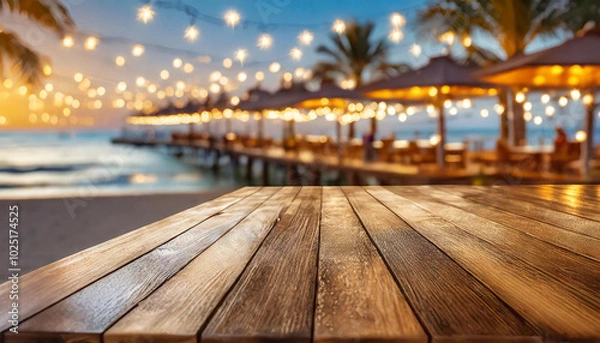 Fototapeta Beautiful beachside wooden table overlooking a stunning pier with glowing lights during sunset
