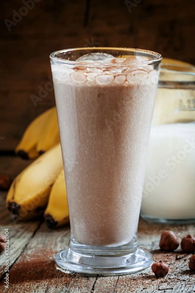 Fototapeta Fresh smoothie banana and chocolate, milk and nuts in a large gl