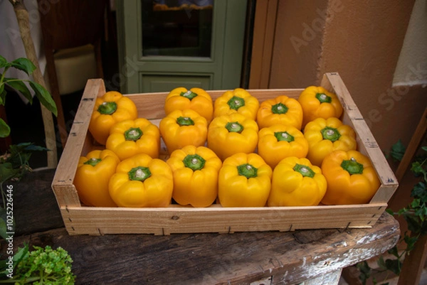 Fototapeta A vegetable crate box of yellow peppers all standing upright in a rustic setting