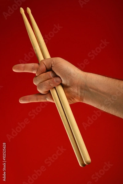 Fototapeta Man hand with drumsticks and devil horns over red