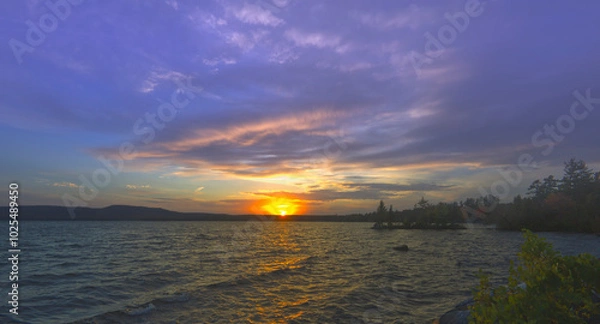 Obraz Sunset over a lake with clouds in the sky