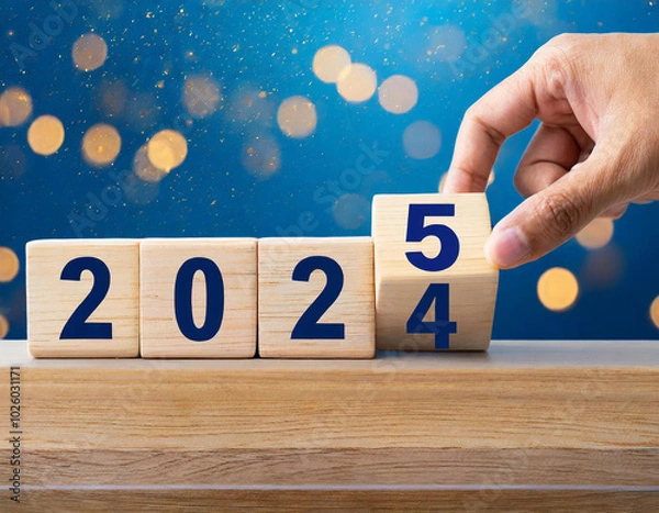 Fototapeta Countdown blocks reveal transition from 2024 to 2025 against a vibrant blue backdrop with bokeh lights