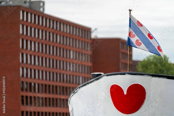 Fototapeta The flag of the province of Friesland, a region in the northern Netherlands. The flag features alternating diagonal stripes of blue and white and seven red "lilies" shaped like hearts.