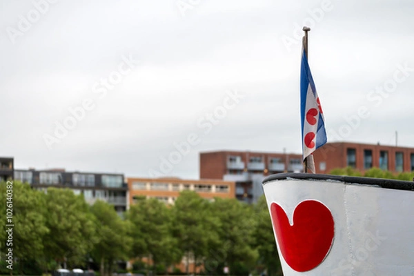 Fototapeta The flag of the province of Friesland, a region in the northern Netherlands. The flag features alternating diagonal stripes of blue and white and seven red "lilies" shaped like hearts.