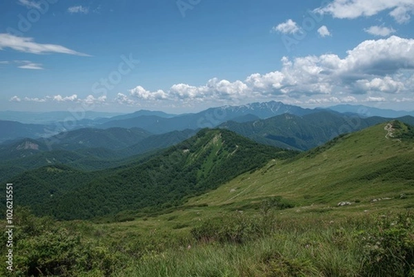 Fototapeta A breathtaking view of rolling hills and distant mountains under a bright blue sky
