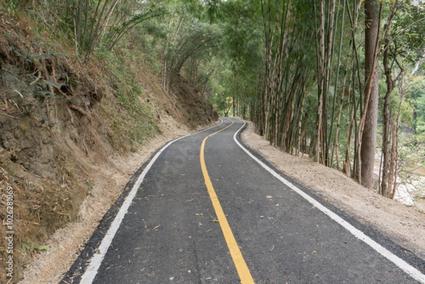 Fototapeta Curve of long road across through mountain view under cloudy sky