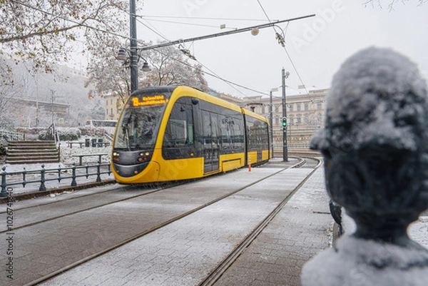 Fototapeta Snowy tram track with tram, buildings in the background, winter, diffused light, Hungary, Budapest, wide angle lens