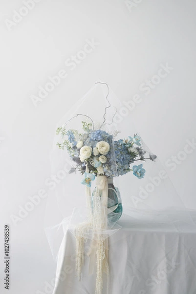Fototapeta Beautiful arrangement of blue and white flowers in a stylish vase on a table against a light background