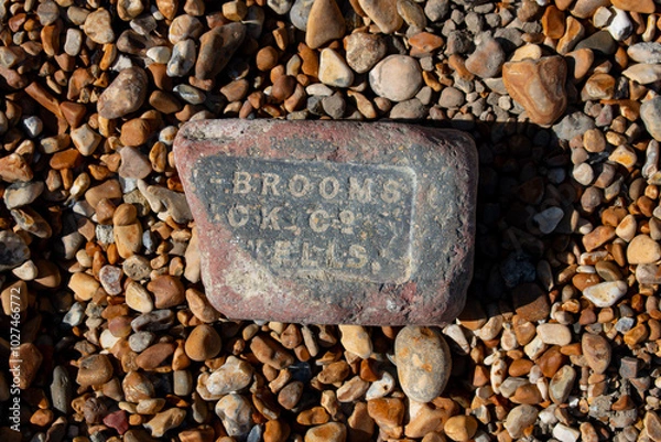 Fototapeta text old stone brickwork washed up on pebble beach 