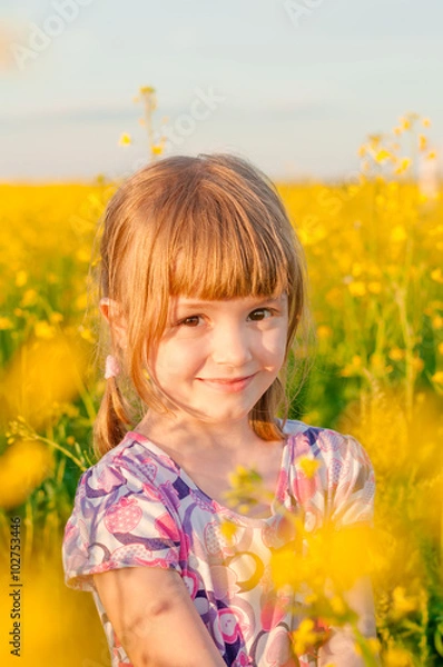 Fototapeta Girl with pigtails in a field of yellow flowers