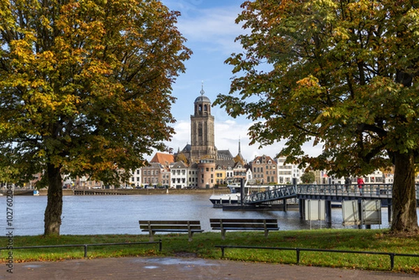 Obraz Autumn cityscape with the skyline of the city of Deventer on the river IJssel with ferries and the tower of the Lebuïnus Church