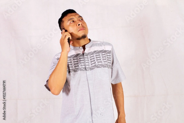 Fototapeta young businessman confused and serious while making a phone call
