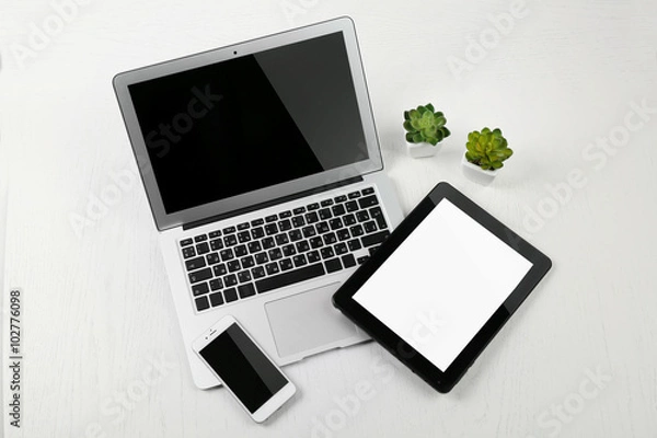 Fototapeta Different modern devices with green plants on light table