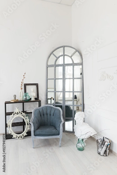 Obraz A stylish corner in a modern room featuring a vintage chair, large mirror, and decorative items in a bright, airy atmosphere