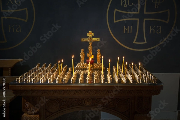 Fototapeta Lighted candles on a stand with golden crusifix in Russian Orthodox Christian cathedral