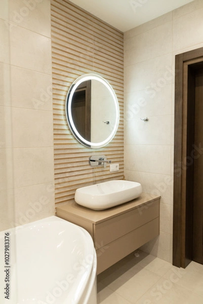 Fototapeta Elegant modern apartment bathroom with innovative design elements featuring a circular mirror and sleek cabinetry