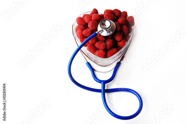 Fototapeta Blue stethoscope and red raspberries shaped in heart