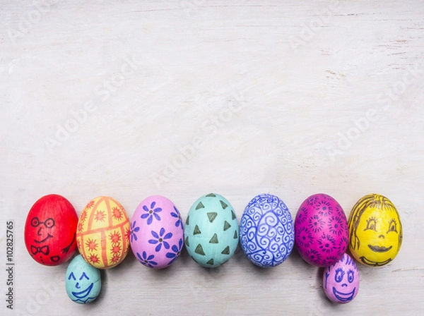 Fototapeta bright, colorful painted eggs for Easter, laid out in a row border place for text  on wooden rustic background top view close up