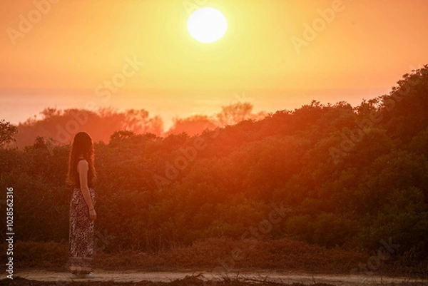 Obraz Brunette brown hair spanish model during sunset. She is thinking looking at the sun in a relaxin environment in Cadiz, Chiclana Sancti Petri area in spain