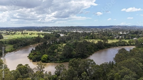 Fototapeta Scenic aerial view of a suburban landscape with a railway line, river, and lush greenery