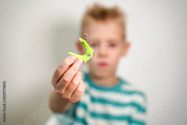 Fototapeta Dentist test setting of palatal braces for young patient in child's hand. Jaw correction