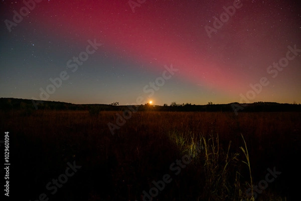 Obraz Moon setting under red aurora arc