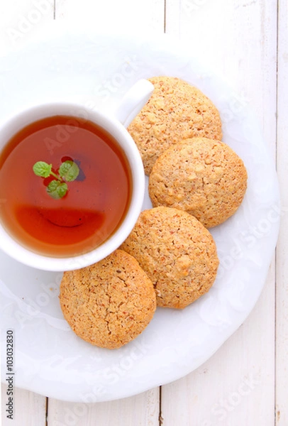 Fototapeta almond cookies in a white plate with a cup of tea