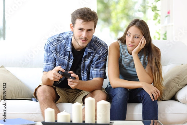Obraz Man playing video games and girlfriend bored beside