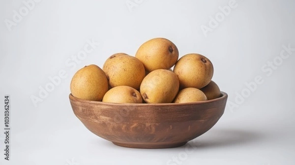 Fototapeta A creative arrangement of chikoo fruit in a bowl, highlighting its color and texture against a clean white backdrop