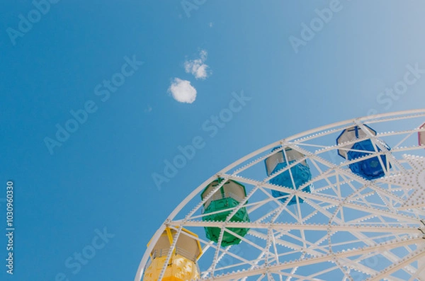 Fototapeta Colourful Ferris wheel set against a bright blue sky with soft clouds on a sunny day at Tibidabo in Barcelona