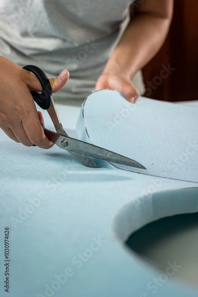 Fototapeta cutting a light blue soft foam for upholstery with scissors detail