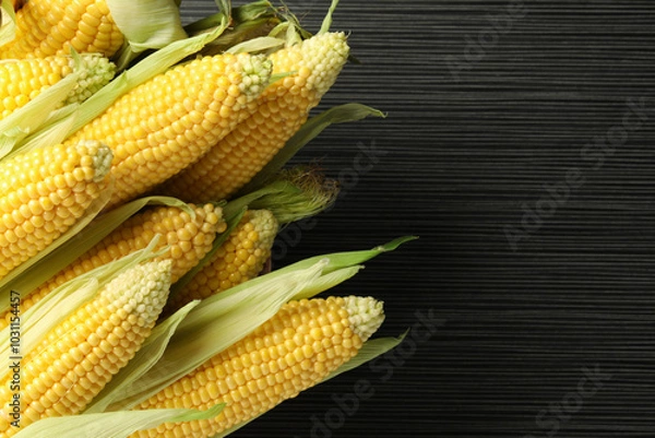 Fototapeta Many fresh ripe corncobs with green husks on wooden table, closeup. Space for text