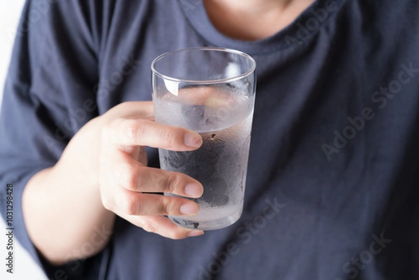 Fototapeta 水の入ったグラスを持つアジア人の中年女性の手元