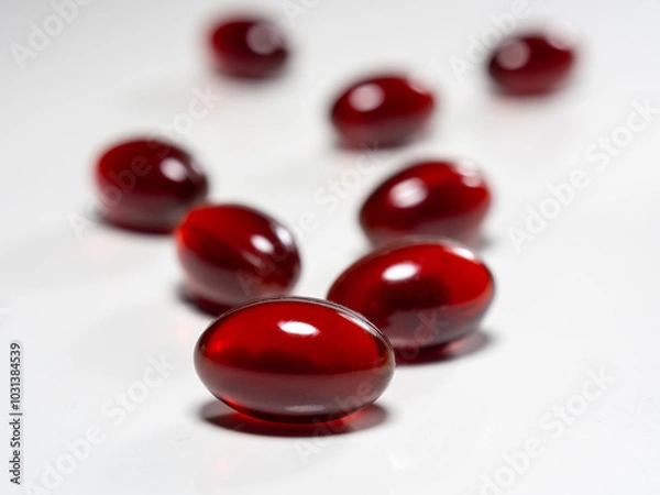 Fototapeta Krill oil capsules on white background. Translucent red softgel capsules of antarctic krill oil. Cardiovascular health. Nutritional supplement with valuable substances
