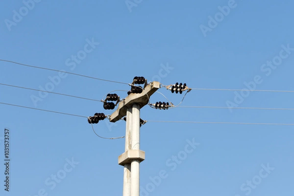 Fototapeta A concrete pole on an electricity transmission line on blue sky background