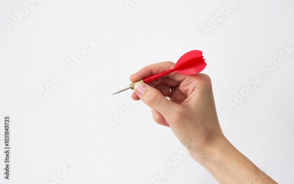 Fototapeta human hand holding a red dart isolated on white background