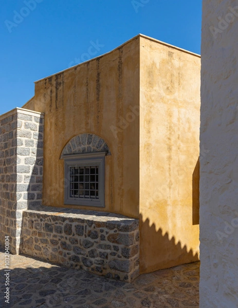 Obraz The warm hues of Hydra's traditional houses blend beautifully under a clear blue sky. Unique architectural details and stonework add character to this picturesque setting.